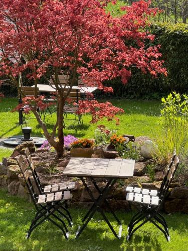 a table and chairs in a garden with a tree at Die "Alte Schmelz"- Boutique-Landhotel & Restaurant in Bad Dürkheim