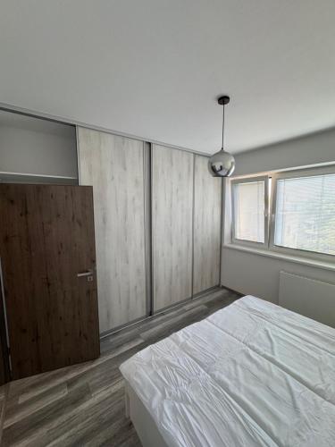a bedroom with a white bed and a wooden cabinet at Apartman David Topoľčany in Topoľčany