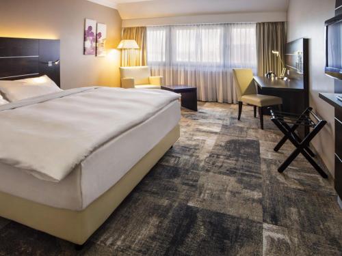 a hotel room with a large bed and a desk at Mercure Hotel Hamm in Hamm
