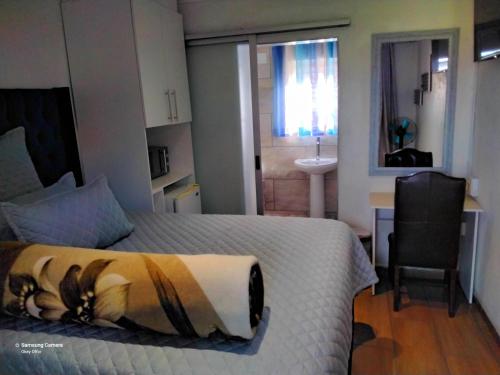 a bedroom with a bed and a bathroom with a sink at Dante Guest house in Alberton