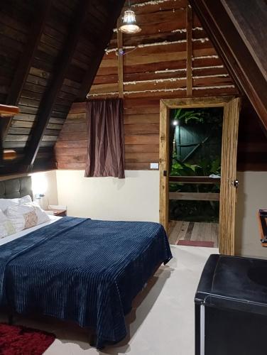 a bedroom with a blue bed and a window at Chalés FRONT LAKE 2 in Córrego do Bom Jesus