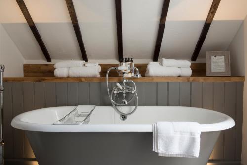 a white bath tub in a bathroom with towels at Tudor Farmhouse Hotel in Clearwell