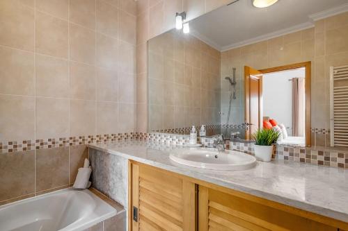 a bathroom with a sink and a tub and a mirror at SUNSET Apartment in Amoreira