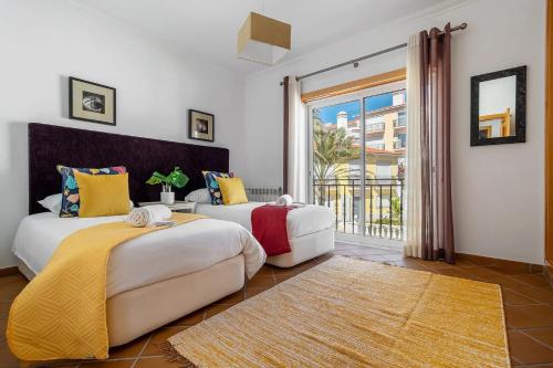 two beds in a room with a large window at SUNSET Apartment in Amoreira