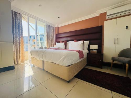 a bedroom with a large bed and a large window at The Sails-Luxe Penthouse By Ezey Tours in Durban