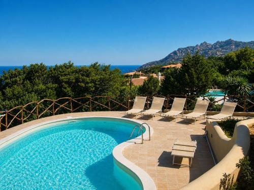 a swimming pool with chairs and the ocean in the background at Villa Turchese - Key to Villas in Costa Paradiso