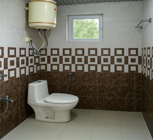 a bathroom with a toilet and a window at Chaman Vatika in Kasol