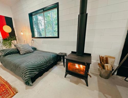 a bedroom with a stove with a bed and a fireplace at Bellingen Disco Studio in Gleniffer