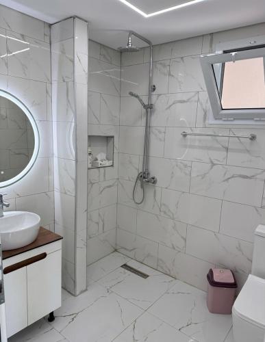 a white bathroom with a shower and a sink at Vila zaho in Dhërmi