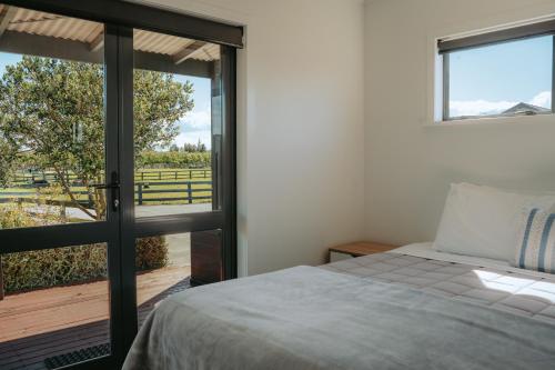 a bedroom with a bed and a sliding glass door at Cottages On St Andrews in Havelock North
