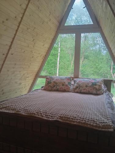 a bed in a room with a large window at A-frame family in Prokurava