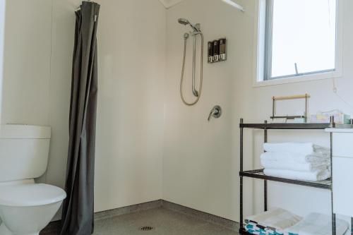 a bathroom with a shower with a toilet and towels at Cottages On St Andrews in Havelock North