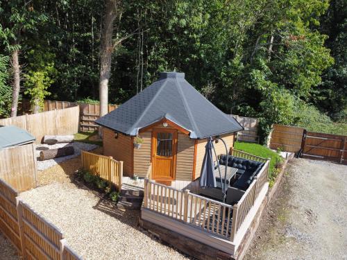a small wooden cabin with a black roof at Woods Meadow Glamping in West Malling
