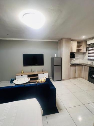 a living room with a blue couch and a flat screen tv at Luxury Executive Apartment in Vanderbijlpark