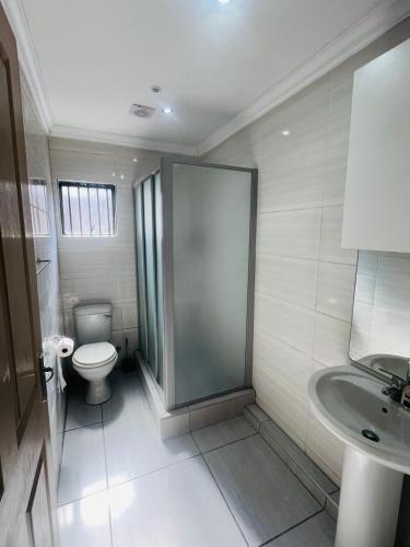 a bathroom with a shower and a toilet and a sink at Luxury Executive Apartment in Vanderbijlpark