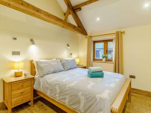 a bedroom with a large bed with a nightstand and a window at 3 Bed in Usk- oc-87286 in Llandenny