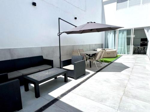 a patio with an umbrella and a table and chairs at The white house in Vecindario