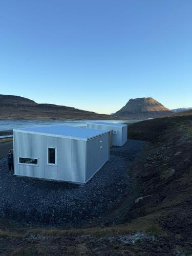 two white modular buildings on a hill with a field at Kirkjufell View Cottages in Grundarfjordur