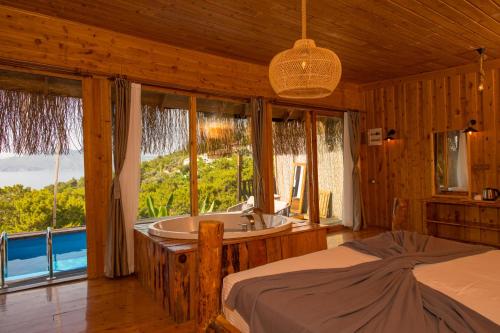 a bedroom with a bed and a tub and windows at Heaven Resort Faralya in Fethiye