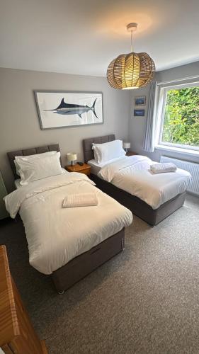 a bedroom with two beds and a chandelier at Ocean View, 3 bed 2 bath, Dog Friendly, Private parking, Beach 9 min walk, sleeps 6 in Ilfracombe
