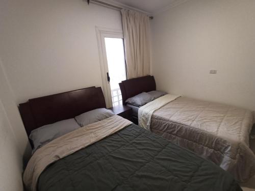two beds in a small room with a window at High quality apartment Madinty in Cairo