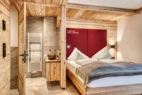 a bedroom with a large bed with a red headboard at Hotel Alpenstolz - Culinary Hideaway Stubai in Mieders