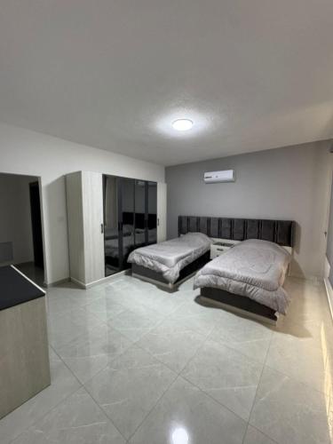 a bedroom with two beds and a tiled floor at aqua chalets شاليهات أكوا in Al Rama