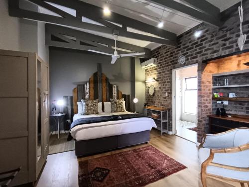 a bedroom with a bed and a brick wall at Earthbound Guest House in Oudtshoorn