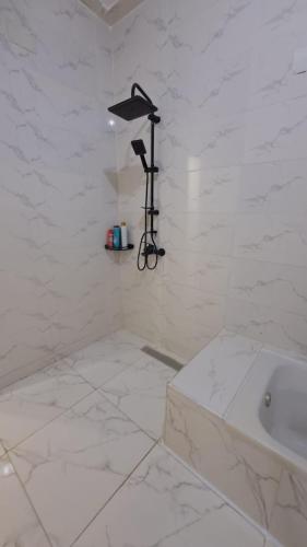 a white bathroom with a tub and a white tile floor at Ruim apartement abo saeed in El Delr