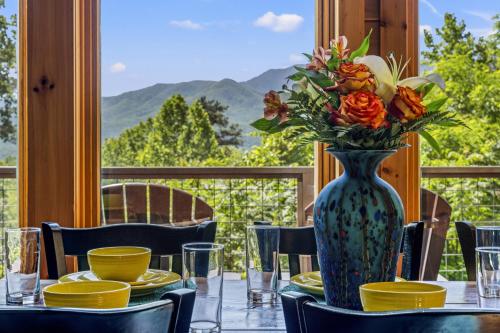 a vase of flowers on a table with a view at A Tree Top View home in Gatlinburg