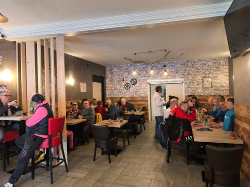 a group of people sitting at tables in a restaurant at Le MUSTANG in Saint-Geniez-dʼOlt