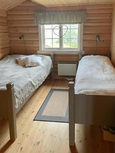 two beds in a wooden room with a window at Cozy, Magical Mountain Cabin With Trails in Etnedal