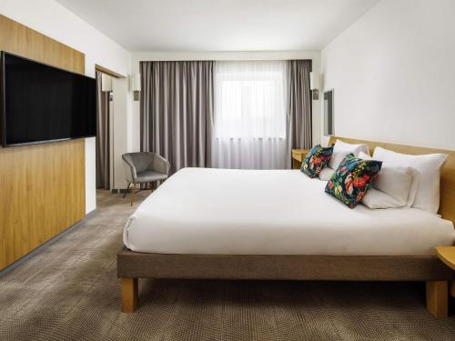 a hotel room with a bed and a flat screen tv at Novotel London Greenwich in London