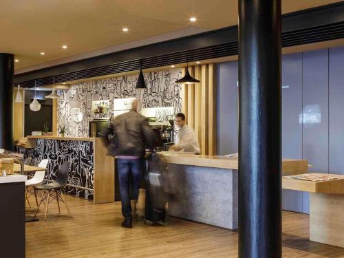 a man walking past a counter in a restaurant at Ibis Granada in Granada