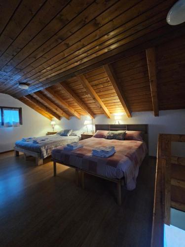 a bedroom with two beds and a wooden ceiling at Eco Mountain Green House in Bienno