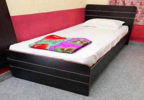 a bed with a black frame and white sheets at Oriland Cottage in Kolli Hills