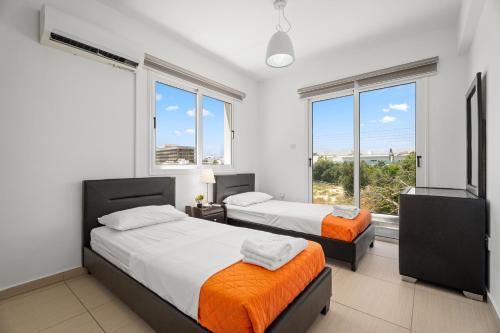 two beds in a room with two windows at Nissini Villas in Ayia Napa