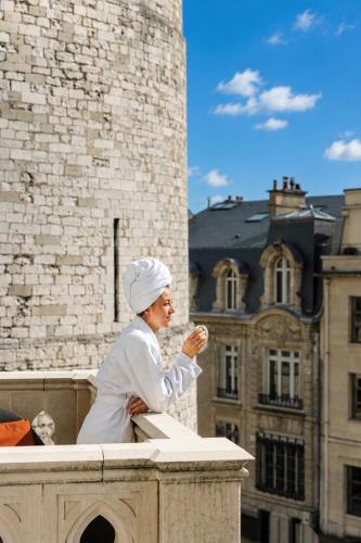 a woman sitting on a ledge in front of a building at Radisson Blu Hotel, Rouen Centre in Rouen