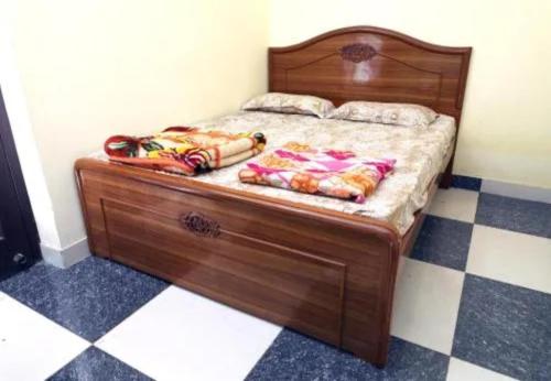 a wooden bed in a room with a checkered floor at Oriland Cottage in Kolli Hills