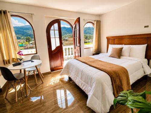 a hotel room with a bed and a table and windows at Mansión Altamirano - Hotel in Talavera
