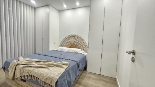 a bedroom with a bed with a blue blanket on it at Costa Nova Azul in Gafanha da Encarnação