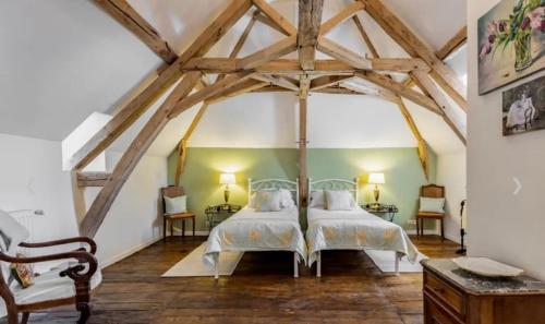 two beds in a large room with wooden beams at Manoir du Village in Irais