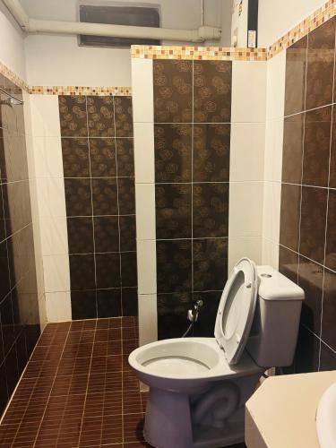 a bathroom with a toilet and a tiled wall at สวนไผ่รีสอร์ท in Ban Na