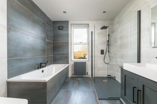 a bathroom with a tub and a shower and a sink at The Grand Weave House in Shipley