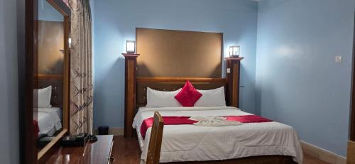 a bedroom with a large bed with red pillows at London House Resort in Birātnagar