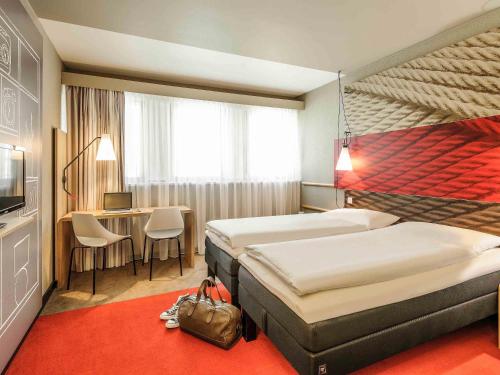 a hotel room with two beds and a desk at ibis Innsbruck in Innsbruck