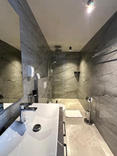 a bathroom with a white sink and a shower at Illyrian Boutique Hotel in Sarandë