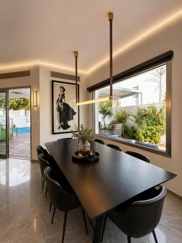 a dining room with a black table and chairs at Villa Gardenya וילה גרדניה אילת in Eilat