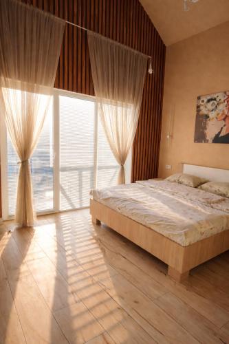 a bedroom with a large bed and a large window at Villa MegaLit - відпочинок у котеджах з чанами біля Косино та Берегово in Velyka Bihanʼ
