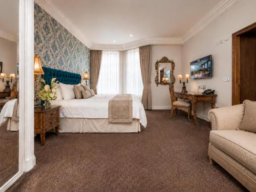 ein Schlafzimmer mit einem Bett, einem Tisch und einer Couch in der Unterkunft Ashburn Hotel in London